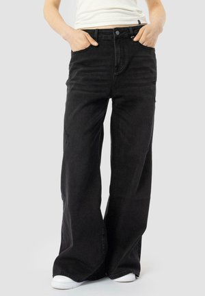 Wide-leg black denim jeans with a high waist, featuring front pockets and subtle distressed detailing. Paired with white sneakers.