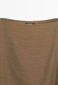 Hellbrauner Strickrock mit einem dezenten strukturierten Muster und einem kleinen schwarzen Etikett mit der Aufschrift "Massimo Dutti" am Bund.