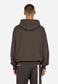 Dunkelgrauer, übergroßer Hoodie mit Kapuze und Kordelzug, gerippten Bündchen und Saum. Weiche Stoffstruktur, minimales Design ohne sichtbare Logos.