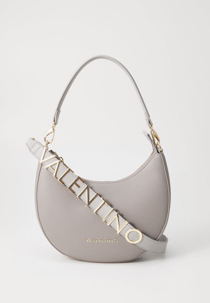 Grå lærveske med et buet design, utstyrt med en gullfarget "VALENTINO" logo-lenke og glatt tekstur. Gullhardware-detaljer inkludert.