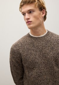 Maglione lavorato a maglia in tonalità marrone e crema, con collo a giro, motivo testurizzato e polsini a costina. Tessuto morbido di peso medio.