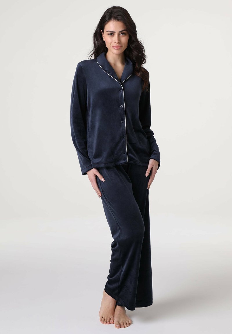 Set di pigiama in blu navy, in tessuto morbido, composto da una camicia con colletto e bottoni decorata con piping bianco e pantaloni lunghi e svasati.