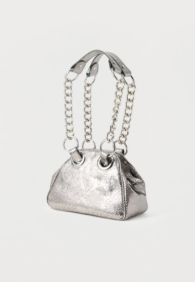 Μικρή μεταλλική ασημένια τσάντα με υφή στην επιφάνεια, μεγάλες ασημένιες αλυσίδες ως χερούλια και δερμάτινες λεπτομέρειες σε λευκό φόντο.