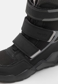 Schwarzer wasserdichter Stiefel mit verstellbaren Klettverschlussriemen, strukturiertem Mesh- und Gummimaterial, robuster Sohle und reflektierenden silbernen Akzenten.