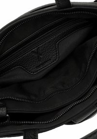 Intérieur d'un sac à main en cuir noir avec une finition texturée, comportant un compartiment principal, une poche zippée et un revêtement en tissu. Design minimaliste.