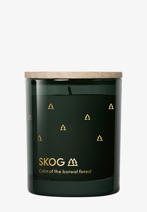Pot à bougie en verre vert avec des silhouettes d'arbres en pins dorés et un couvercle en bois clair. L'étiquette indique "SKOG - Calme de la forêt boréale."