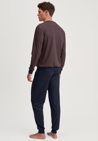 Haut à manches longues, à motifs en bleu foncé et rouge avec des poignets côtelés, associé à un pantalon navy uni et fuselé, le tout en tissu doux.