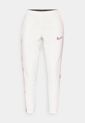Pantaloni da allenamento bianchi Nike con strisce laterali rosa e logo. Vita elastica, design a gamba affusolata, texture liscia, adatti per abbigliamento sportivo.