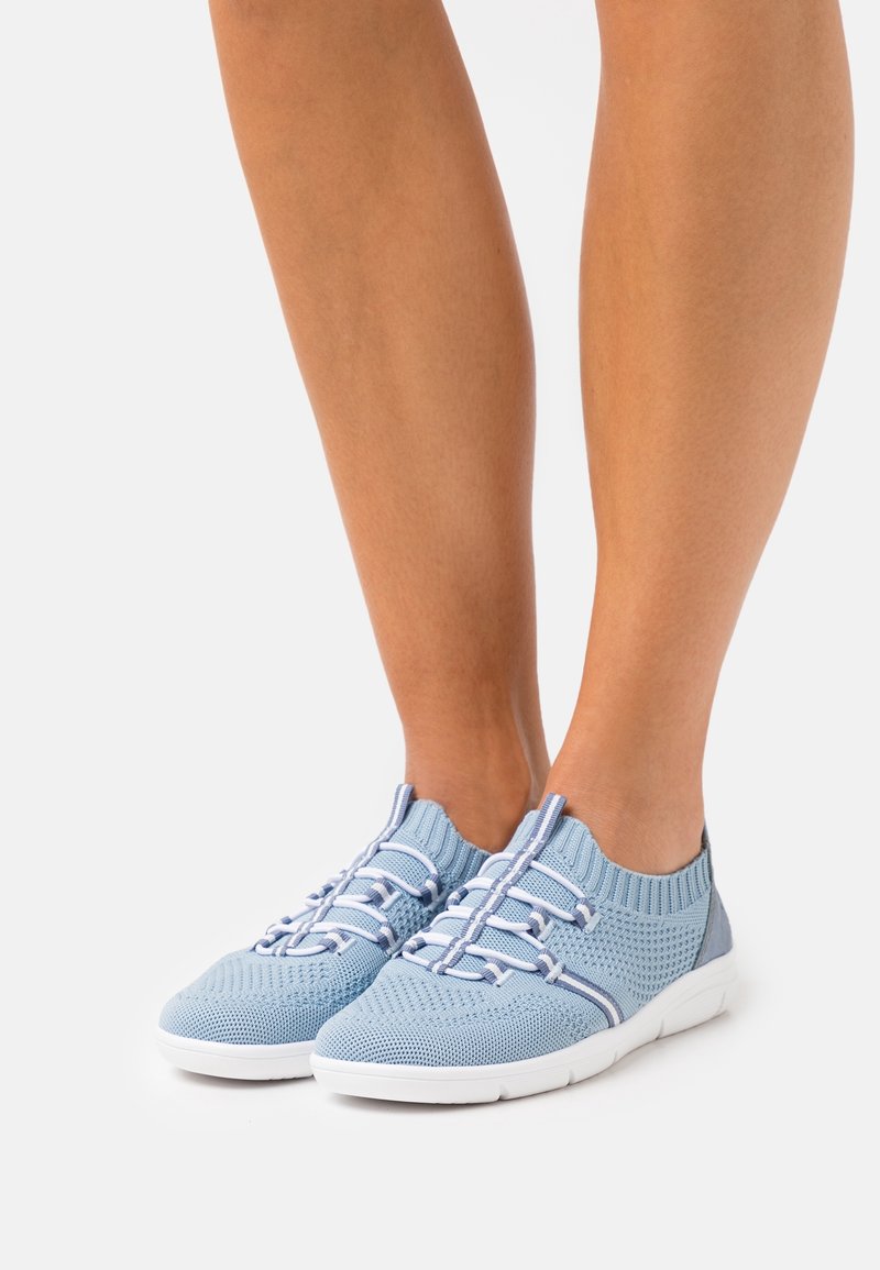 Ljusblå stickade sneakers med en andningsbar struktur, elastiska snören och en vit gummisula. Har en kontrasterande blå hälpanel.