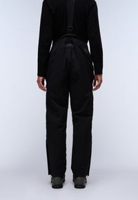 Zwarte waterdichte skibroek met verstelbare banden, taps toelopende pijpen en ritssluitingen bij de enkels, gemaakt van een duurzame, gestructureerde stof.