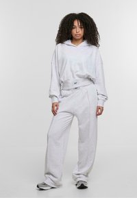 Lysegrå, blød hoodie med bred krave, parret med løstsiddende, matchende sweatpants. Begge har et rent design og elastisk talje.