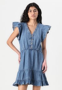 Denimkjole med V-hals, voluminøse ermer og innsamlet midje. Har knapper foran og et lagdelt, utsvingt skjørt.