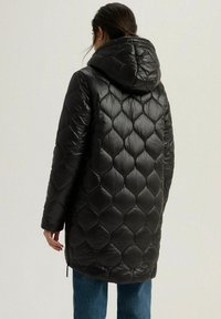 Czarna pikowana długa kurtka z kapturem. Posiada błyszczące wykończenie i wzór w diamenty. Prosty krój, boczne kieszenie na zamek i luźny krój.