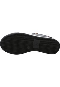 Schwarze Gummisohle mit strukturierten Oberflächen und eingeprägtem Logo, mit einem kontrastierenden weißen Rand.