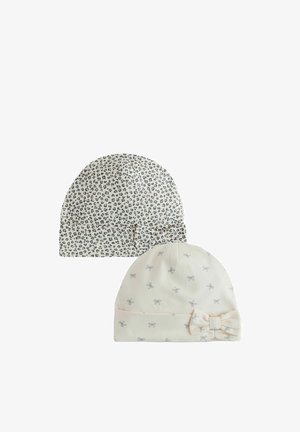 Zwei weiche Baby-Mützen, eine weiße mit grauen Schleifen und einem Schleifen-Akzent, die andere weiße mit schwarzen Leopardenflecken und einem Schleifen-Akzent.