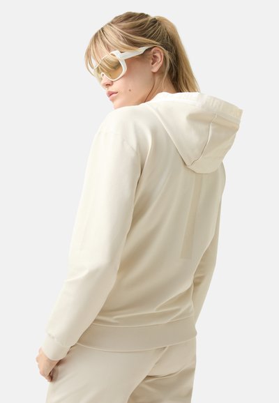 Light beige hoodie with a jersey texture, drawstring hood, and ribbed cuffs. Features a subtle logo on the back and side stripe design.