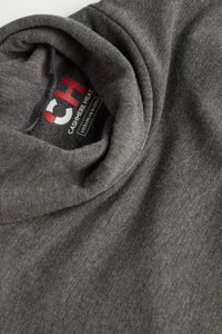 Šedý, měkký úpletový rolák s ohrnutým límcem a přišitým štítkem s nápisem "CASHMERE HEAT" a "intm slim" tučným písmem.