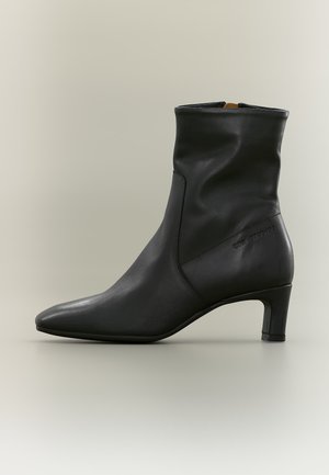 Schwarzer Leder-Stiefelette mit spitzer Zehenkappe und niedrigem Absatz, glatter Textur und dezenter Markenprägung an der Außenseite.
