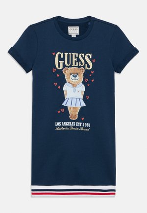 Vestido azul marino de manga corta con un osito de peluche vestido de marinero, corazones rojos, logo "GUESS" y dobladillo a rayas en rojo, blanco y azul marino.