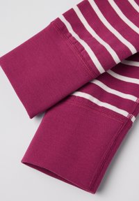 Vaaleanpunainen kangas, jossa on valkoisia vaakaraitoja. Tekstuuriltaan sileä ja ribattu hiha, joka näyttää siistiä ompelua reunoilla.