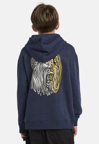 Sweat à capuche bleu marine avec un grand graphique coloré d'un visage au dos. Fabriqué en tissu doux et texturé, avec une coupe décontractée et une capuche réglable.