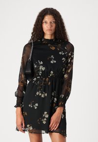 Rochie neagră cu imprimeu floral, cu mâneci translucide lungi, talie strânsă și decolteu ondulat; prezintă modele de flori albe și maro. Include o poșetă mică neagră.