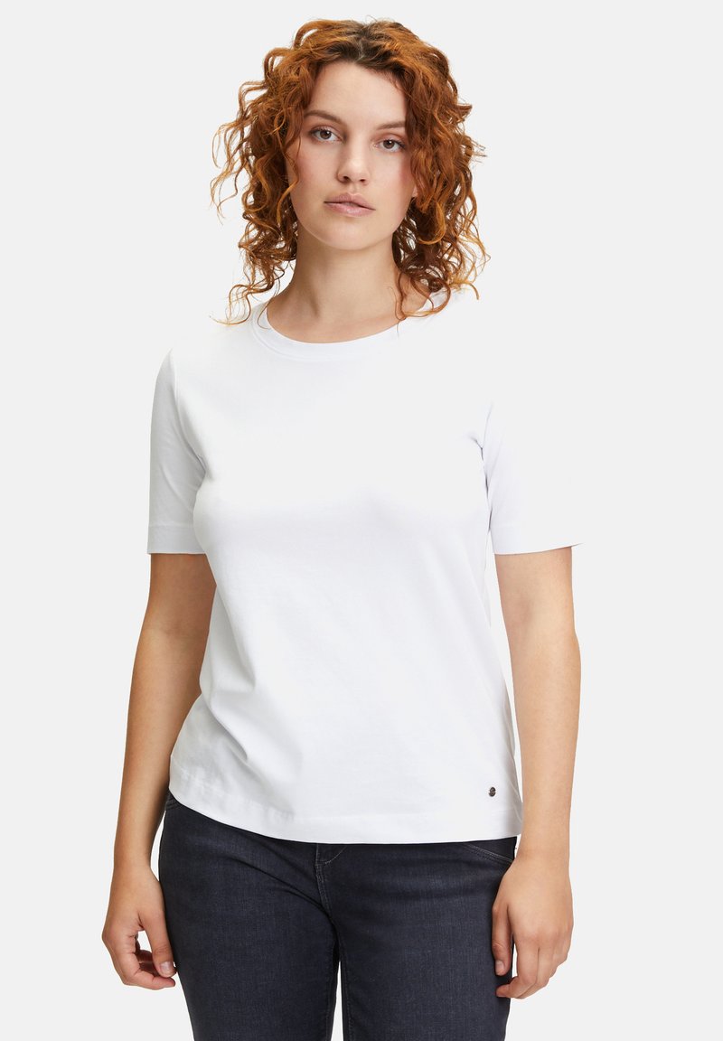 Biała bawełniana koszulka z krótkim rękawem, okrągłym dekoltem, luźnym krojem, z małym logo akcentującym przy dolnym brzegu i gładką fakturą.