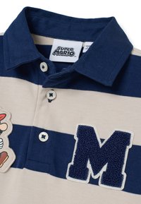 Polohemd mit horizontalen Streifen in Marineblau und Creme. Mit einem weichen "M"-Patch und einem Cartoon-Charaktergrafik. Drei Knöpfe am Kragen.