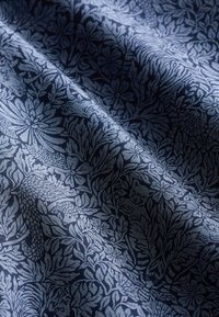 Tekstiil, mille taustaks on tume mereväesinine ning millel on heledamate siniste toonidega üksikasjalik lillemuster, mis kujutab keerukaid lehtede ja lillede motiive.