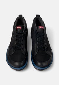 Zapatos negros con parte superior sintética, cordones texturizados, puntera redonda y una suela de goma azul. Incluye la marca Camper en la lengüeta.