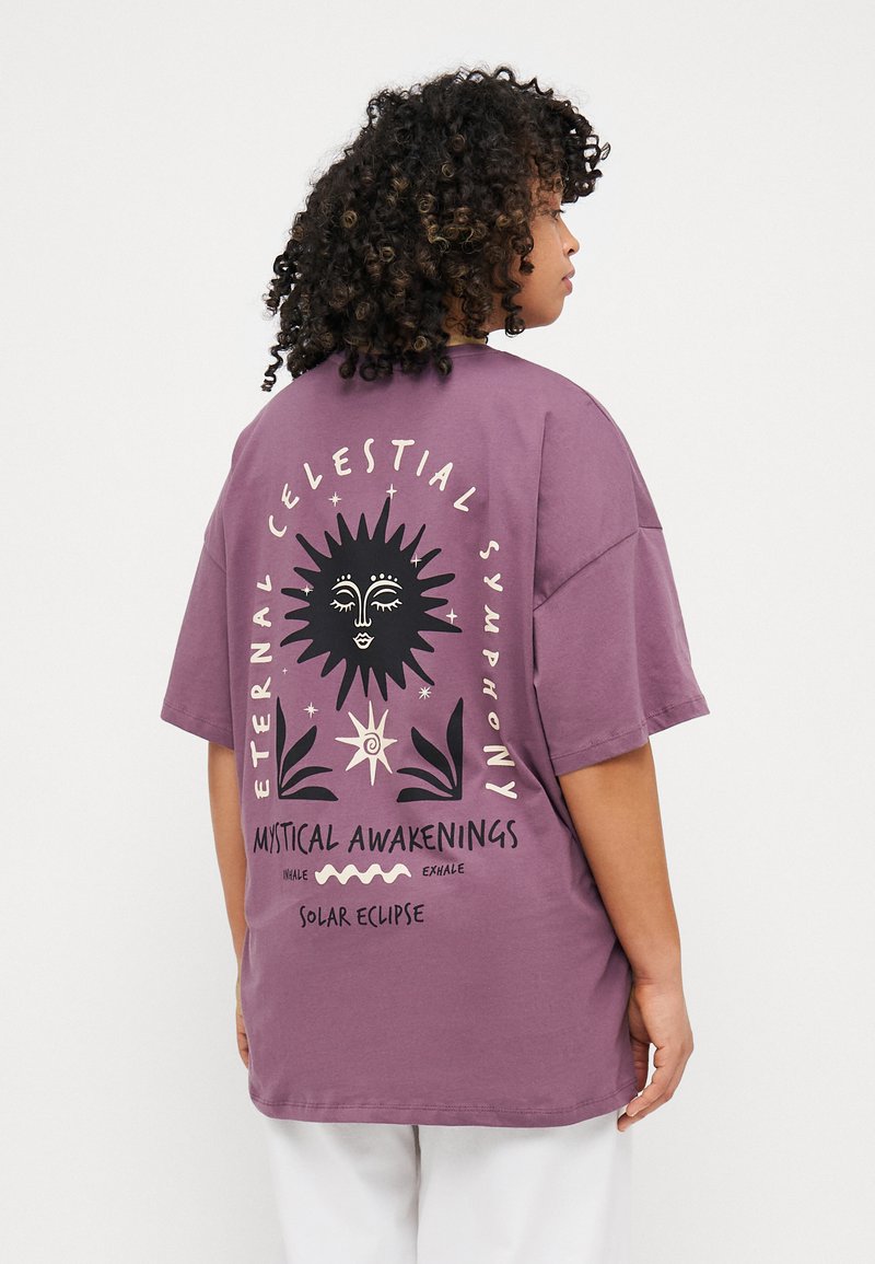 Purple oversized t-shirt featuring a black sun graphic and text on the back, made from soft cotton fabric with short sleeves.