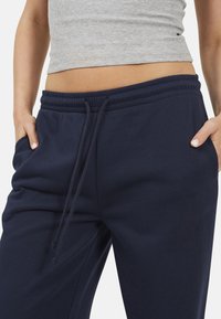 Pantaloni sportivi blu navy realizzati in tessuto morbido, dotati di una vita elastica con stringa, tasche laterali e una vestibilità comoda.