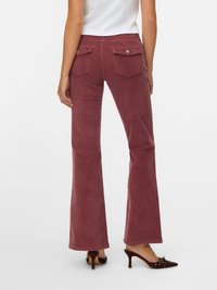 Burgundske široke hlače od kordura s dva stražnja džepa i srebrnim detaljima. Uparene s smeškastim cipelama na petu. Glatka tekstura, srednji struk.