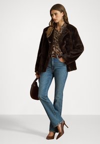 Barna műszőrmegéret, fodros barna blúz, világoskék farmernadrág és barna magassarkú cipők. Tartalmaz barna kézitáskát és öv részleteket.