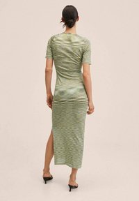 Abito midi verde aderente con maniche corte, caratterizzato da un motivo testurizzato e ondulato e una spaccatura laterale. Tessuto morbido e design minimalista.
