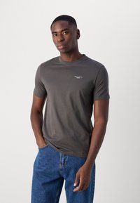 Tricou gri cu mânecă scurtă, din bumbac, cu un guler rotund și un mic logo alb pe piept, asortat cu blugi din denim albastru.