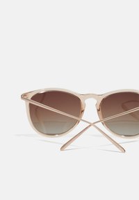 Round sunglasses with a light pink frame, gradient brown lenses, and slender arms. The arms have a subtle brand engraving.