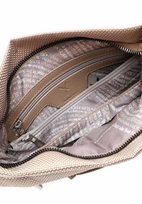 Interno della borsa beige con texture, dotato di tasca con zip, caratterizzato da una morbida fodera con un motivo di testo stampato in grigio chiaro e accenti scuri.