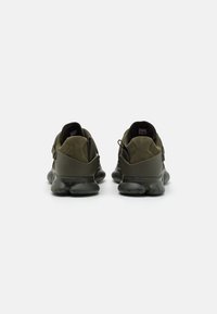Scarpe sportive di colore verde scuro con tomaia in suede e materiale sintetico, suola intermedia texturizzata, collarino imbottito e linguetta per una facile calzata.