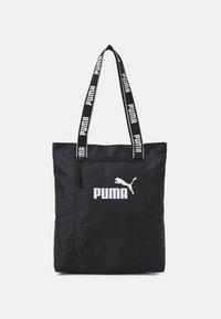 Zwarte nylon draagtas met dubbele handvatten. Voorzien van een wit PUMA-logo en kattensilhouet. Met ritssluiting aan de bovenkant. Versterkte stiksels.