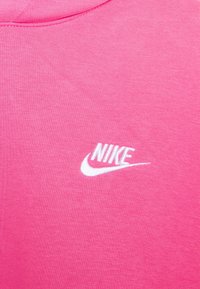 Rosa tyg med vit broderad Nike-logotyp och swoosh nära kragen.