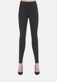 Czarne legginsy z elastycznego materiału, z wysokim stanem i gładką, matową fakturą, zestawione z czarnymi szpilkami.