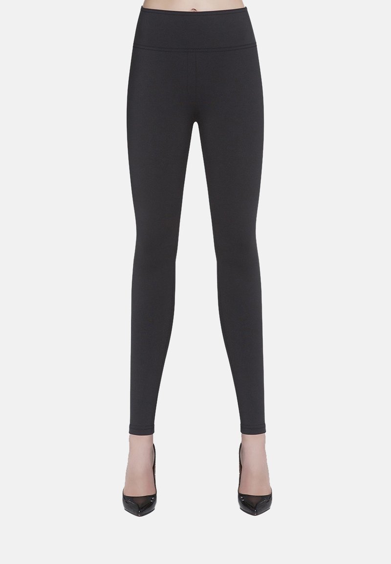Czarne legginsy z elastycznego materiału, z wysokim stanem i gładką, matową fakturą, zestawione z czarnymi szpilkami.