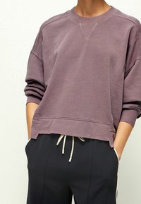 Fialová mikina s raglánovými rukávy a krátkým střihem, s žebrovaným výstřihem a lemem, vyrobená z měkké, strukturované látky.