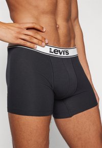 Μαύρα βαμβακερά μποξεράκια με λευκό λογότυπο Levi's στην ελαστική μέση. Κομψή εφαρμογή με απαλή υφή και μεσαίου μήκους κάλυψη.