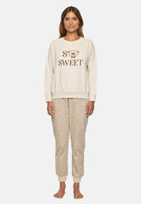 Felpa crema con testo "SO SWEET" e grafica di un orso; abbinata a pantaloni tuta beige con stampa leopardata. Entrambi realizzati in tessuto morbido.