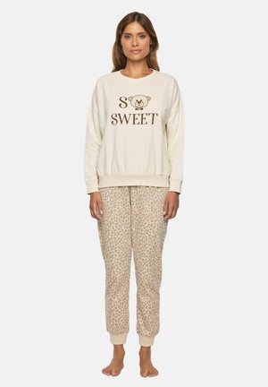 Sudadera crema con el texto "SO SWEET" y un gráfico de oso; combinada con pantalones de chándal beige con estampado de leopardo. Ambos hechos de una tela suave.