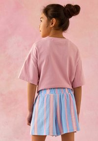 Lichtroze katoenen T-shirt met korte mouwen, gecombineerd met blauw en roze gestreepte textuuroveralls, met elastische tailleband, bekeken vanaf de achterkant.