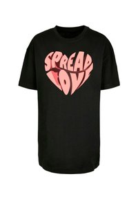 Camiseta de algodón negra con un gráfico de corazón que presenta la frase "DIFUNDE AMOR" en letras estilizadas rosas y rojas. Manga corta, corte holgado.