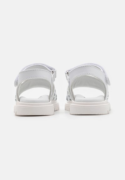 White open-back sandals with a textured upper and adjustable strap, featuring a cushioned sole and a smooth rubber outsole.